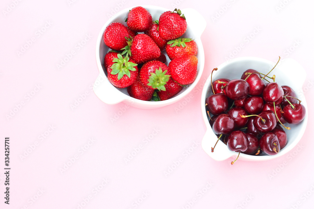 Ripe berries - strawberries and cherries in a plate. Still life with strawberries and cherries on pink background. Ripe berries - strawberries and cherries in a plate. Still life with strawberries and cherries on pink background.