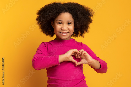 Adorable Little African American Girl Showing Heart Gesture With Hands photo