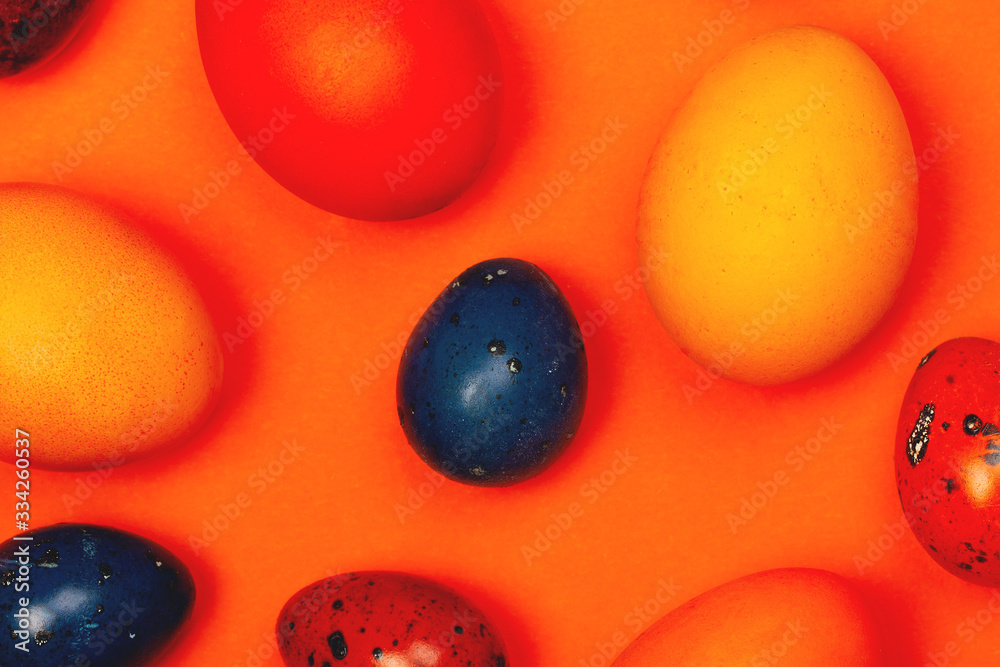 Easter eggs in trendy colors on the orange background. The concept of stylish decoration for Easter, minimalistic, greeting cards, etc.