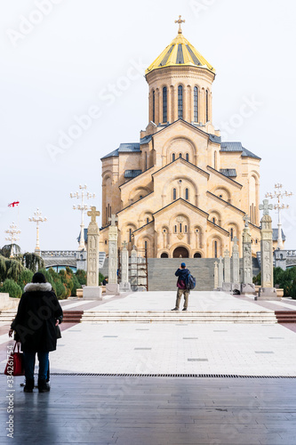Tourist standing around and taking photographs of holy trinity cathedral In Tbilisi with cathedral standing on the background.Georgi 06.03.2020