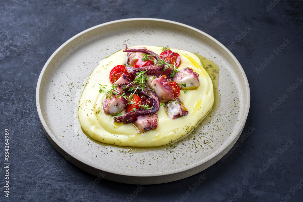 Traditional Italian polpo alla griglia su crema di patate with barbecued octopus, potato creme and tomatoes as closeup on a modern design plate Traditional Italian polpo alla griglia su crema di patate with barbecued octopus, potato creme and tomatoes as closeup on a modern design plate