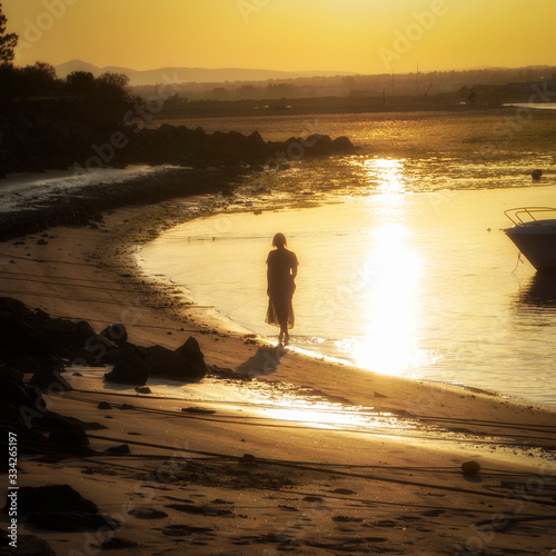 Joven mujer paseando melancólica por la playa de Tavira al atardecer  photo