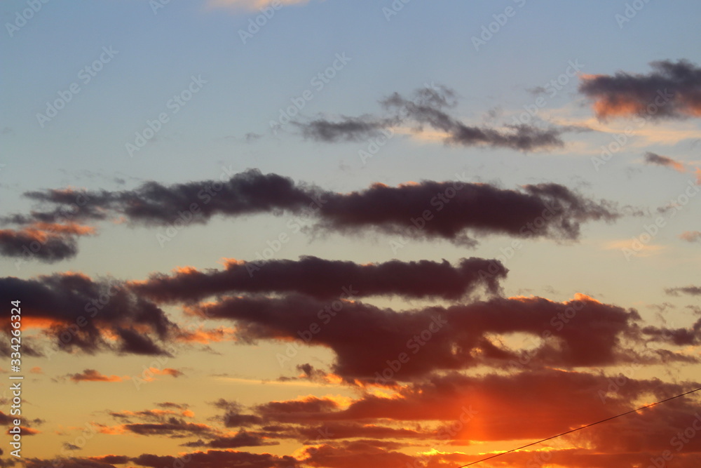 Fototapeta premium Clouds in the blue sky at sunset or dawn backlit by the sun. Place for text and design.