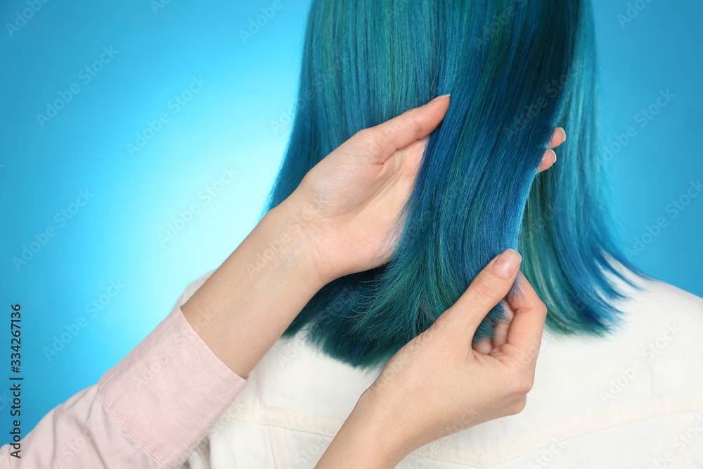 Fototapeta premium Woman with bright dyed hair on light blue background, back view