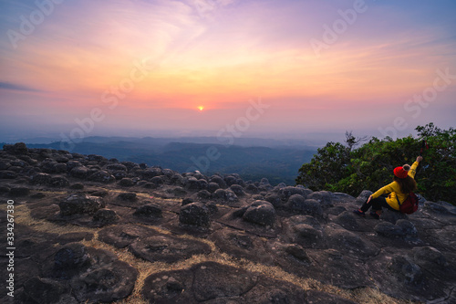 Tourists sit with arms and watch the sunset over the rocky line at Phu Hin Rong Kla National Park, Phitsanulok Province.