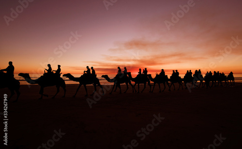 Western Australia - Camel ride at the sunset with silhouette of tourists on Cable Beach in Broome