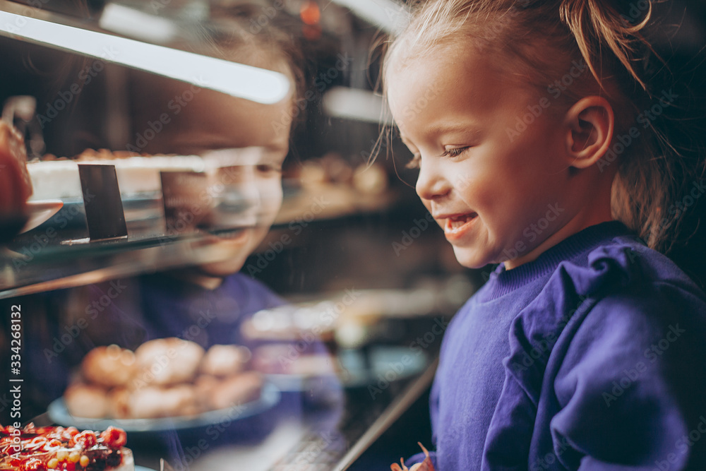 little pretty girl chooses pastries in a cafe. a child next to a showcase with goods