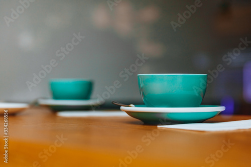 Close up of hot tasty fresh cappuccino on wooden table with napkins in greenery ceramic cup with blur background. Morning hot drinks made by professional barista for client.