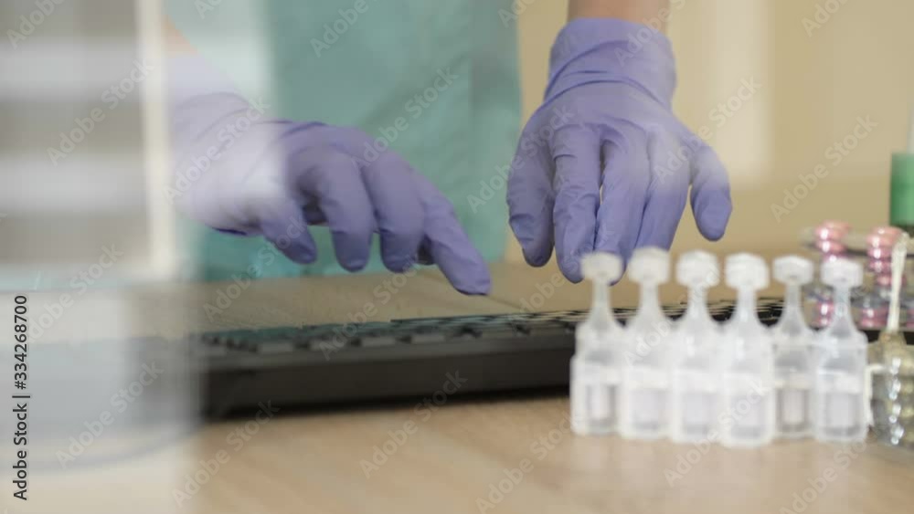 Desktop of a medical worker. Computer keyboard, medication. The doctor s hands are protected by disposable gloves. Desktop of a medical worker. Computer keyboard, medication. The doctor s hands are protected by disposable gloves.
