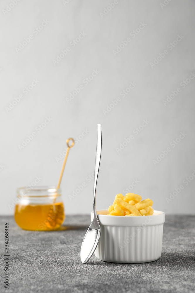 National food cuisine of the Middle East. Sweet dessert made of dough and honey chak-chak in a ceramic white bowl and a teaspoon on a gray concrete table. Vertical orientation, copy space. National food cuisine of the Middle East. Sweet dessert made of dough and honey chak-chak in a ceramic white bowl and a teaspoon on a gray concrete table. Vertical orientation, copy space.