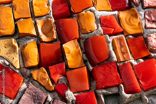 Bright orange,red and yellow square stones in a mosaic on the wall close up.Abstract texture,creative background,selective focus © Tatyana