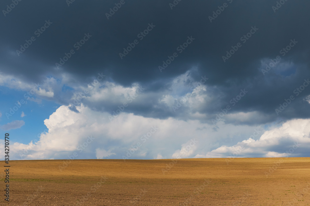 Freshly plowed land and ovescast blue sky with storm clouds Freshly plowed land and ovescast blue sky with storm clouds