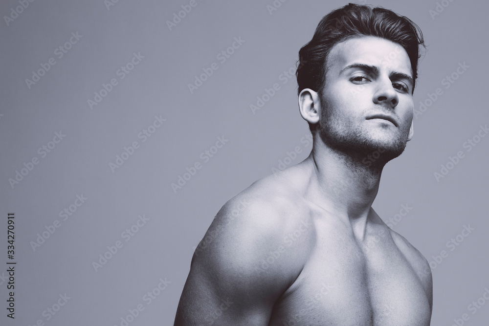 Fototapeta premium Male beauty concept. Portrait of handsome young man with stylish haircut posing over gray background. Perfect hair & skin. Close up. Studio shot