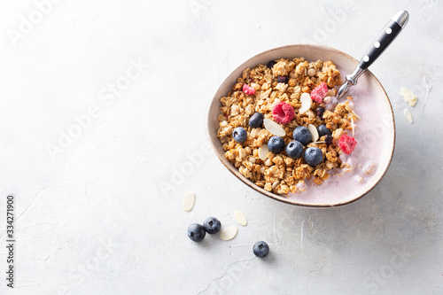 Breakfast. Cereal muesli with yogurt, blueberries, raspberries, almonds and honey on a light background. Space for text. Top view.