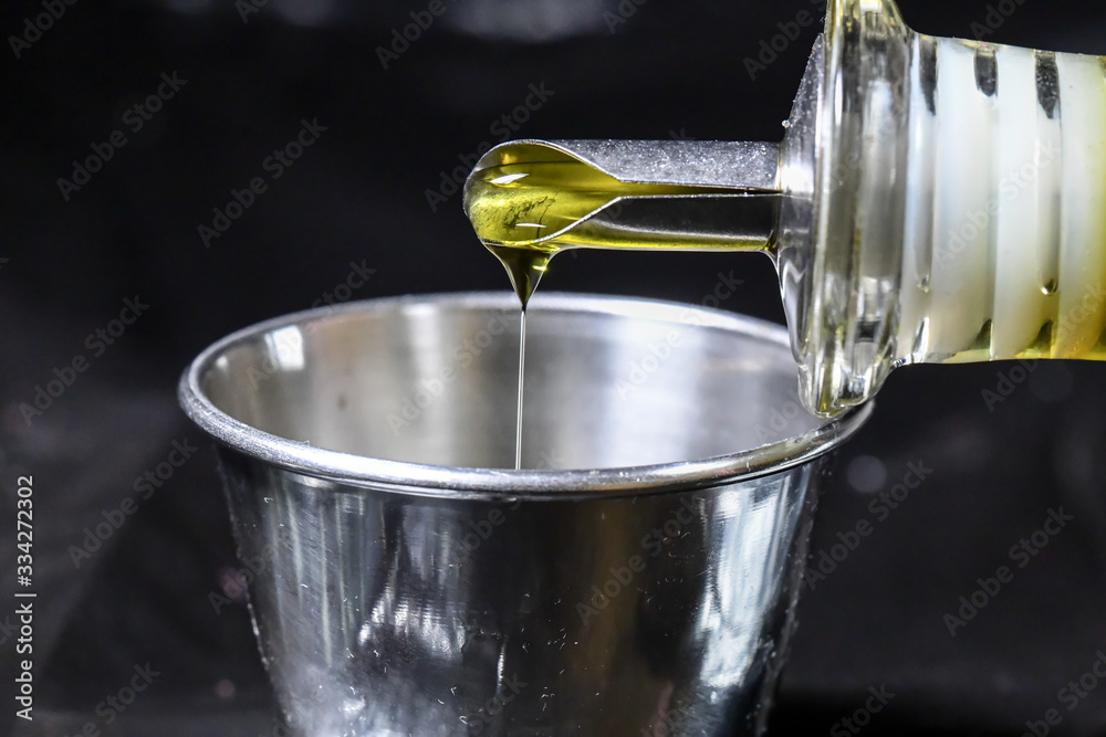 Pouring olive oil in metal cup Pouring olive oil in metal cup
