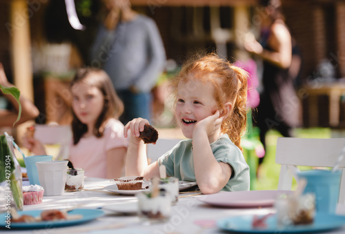 Small children eating on summer garden party, birthday celebration concept.