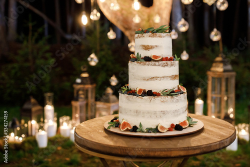 Beautiful delicious white wedding cake at the evening. Wedding cake for guests and brides