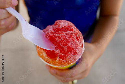 Close up of a colorful snow cone being eaten with a spoon
