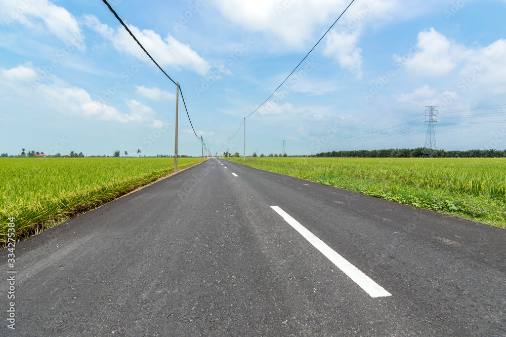 Asphalt road in rural and paddy farm with blue skies in Selangor, Malaysia