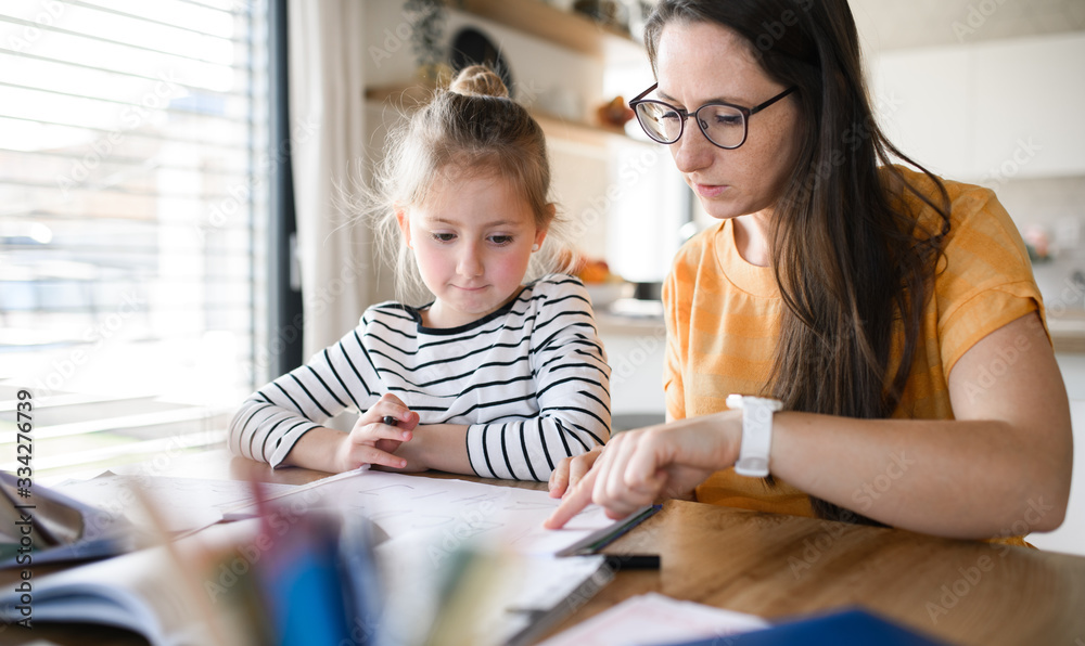 Mother and daughter learning indoors at home, Corona virus and quarantine concept.