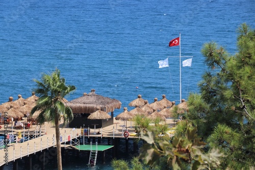 Turkish flag on a flagpole in the background hotel beach and the Mediterranean sea