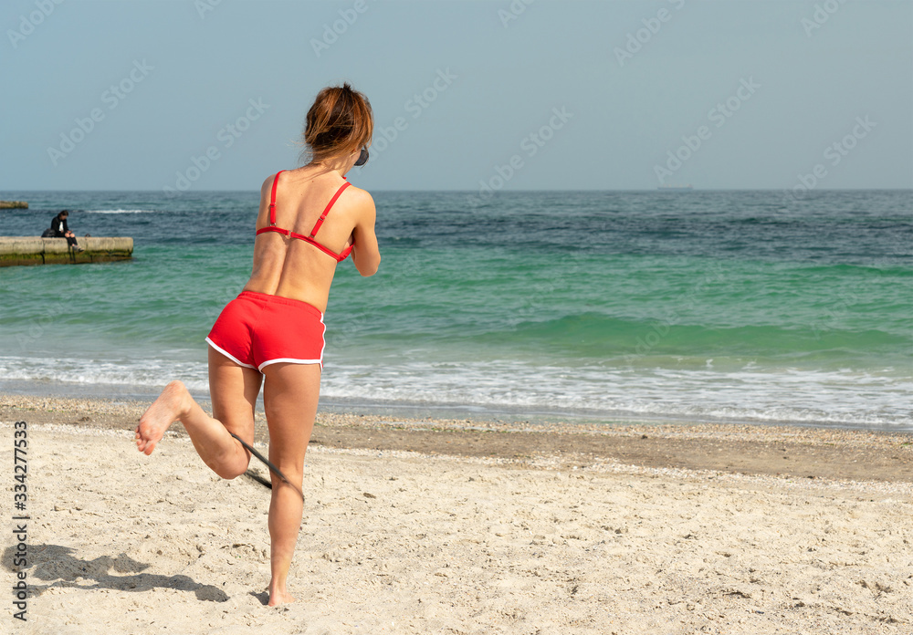 Young sportive girl training gymnastics on sea sand beach, Odessa, Ukraine