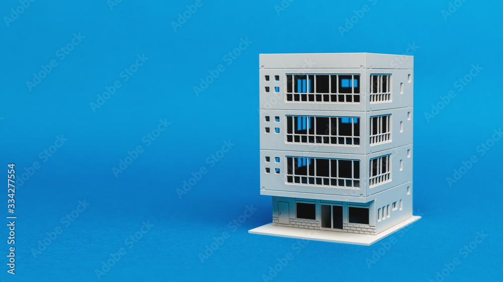 Model of a building balancing on one edge on a light blue background Model of a building balancing on one edge on a light blue background