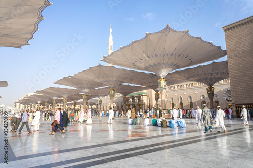 MEDINA - MARCH 06 : Pilgrims walk underneath giant umbrellas at Nabawi Mosque compound on March 06, 2015 in Medina, Kingdom of Saudi Arabia. Nabawi mosque is the second holiest mosque in Islam.. photo