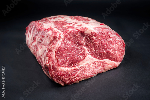 Raw dry aged wagyu entrecote beef steak roast as closeup on a black background with copy space