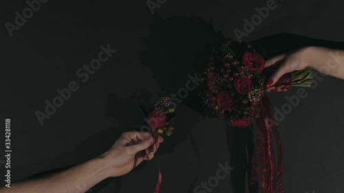 Hands on a black background with a red bouquet and men's with a buttonhole as in the picture of Creation of Adam by Michelangelo photo