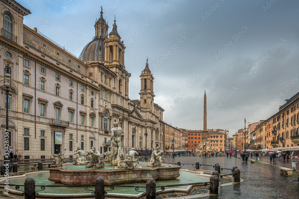 Fototapeta premium Przepięknie rzeźbione fontanny oraz katedra na Piazza Navonna w Rzymie. Pochmurny i deszczowy dzień. Włochy, Europa