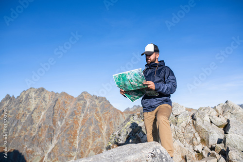 Mature man hiking in mountains in summer, using map.