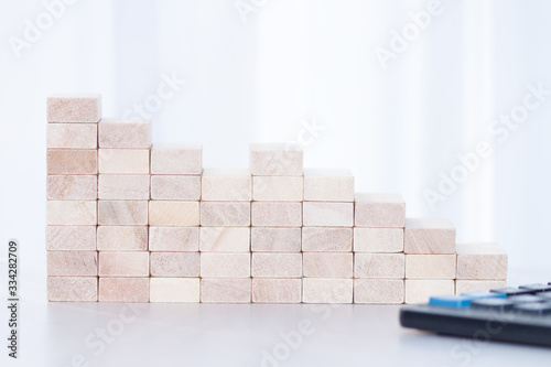 Stack of wooden blocks, calculator on whete sunlight background. Step down, fall, recession, crisis concept. photo