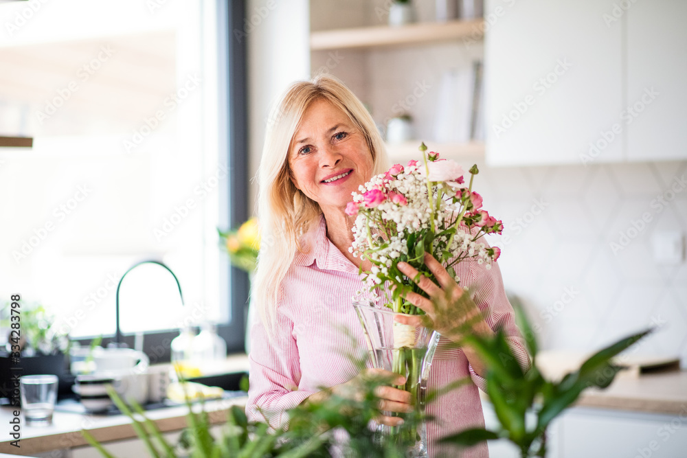 Portrait of senior woman arranging flowers in vase indoors at home. Portrait of senior woman arranging flowers in vase indoors at home.