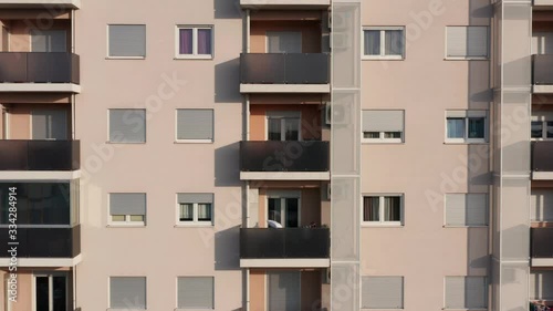 Exterior of a high-rise multi-story apartment building - facade, windows and balconies. Establishing shot aerial footage.