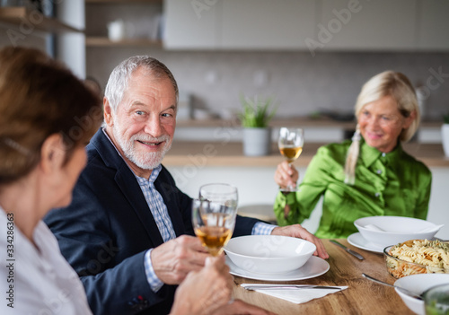 Group of senior friends at dinner party at home, with glasses of wine.