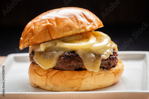 Cheeseburger pão com queijo e requeijão derretido em prato quadrado com fundo escuro 