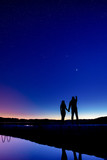 Silhouette of a couple in love on the pier. Silhouette of a couple in love on a background of the starry sky. Planets Venus in the night sky.