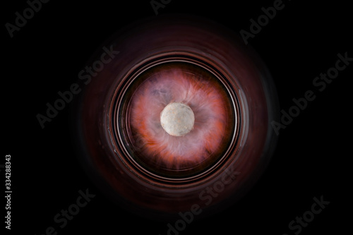 Rote Schokolinse löst sich im Wasserglas, optisch ähnlich einem Planeten im All.