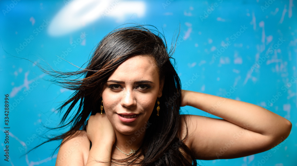 Hair Care. Portrait of beautiful brunette woman with long shiny flying hair posing over Turquoise
background Hair Care. Portrait of beautiful brunette woman with long shiny flying hair posing over Turquoise
background