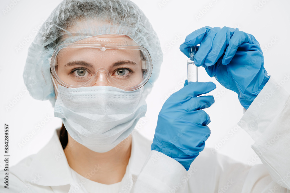 young scientist in mask holds ampule with medicine for coronavirus in clinic young scientist in mask holds ampule with medicine for coronavirus in clinic