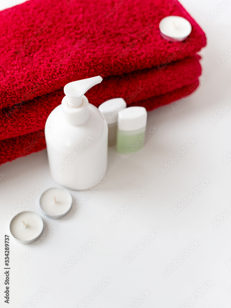 Disinfectant container, white background, soap dish, for hygiene and cosmetics, minimalism, small jars for shampoo and shower gel, candles, red bath towel for the body, hotel bath set Disinfectant container, white background, soap dish, for hygiene and cosmetics, minimalism, small jars for shampoo and shower gel, candles, red bath towel for the body, hotel bath set