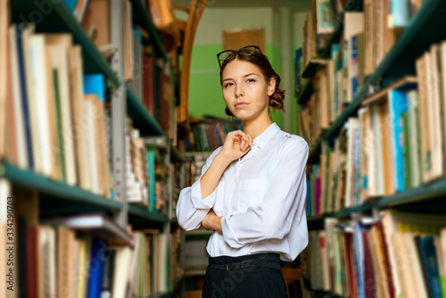 A nice woman in a white shirt in the library is smiling