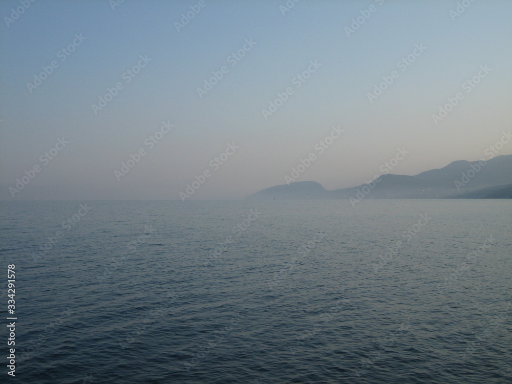 Rocky coast at sunset. In the distance, the coast mountains loomed in the mist.