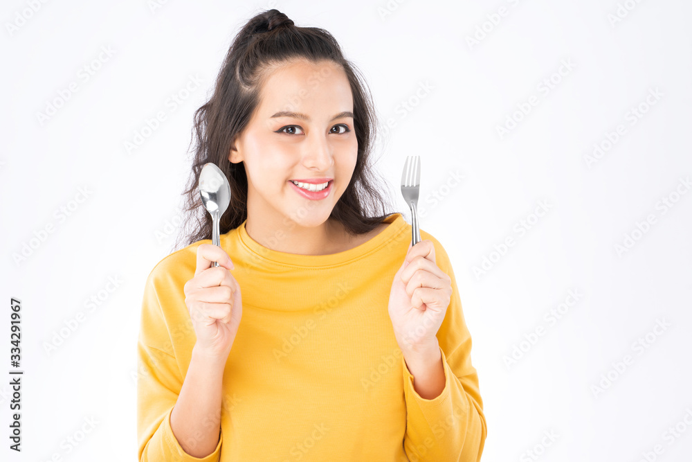 Young beauty Asian woman showing spoon and fork prepare to eat food and she wearing a yellow sweater shot isolated on white background Young beauty Asian woman showing spoon and fork prepare to eat food and she wearing a yellow sweater shot isolated on white background