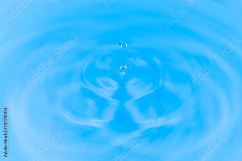 Closeup to water drops making circles on the surface. Amazing blue color background. Natural beauty.