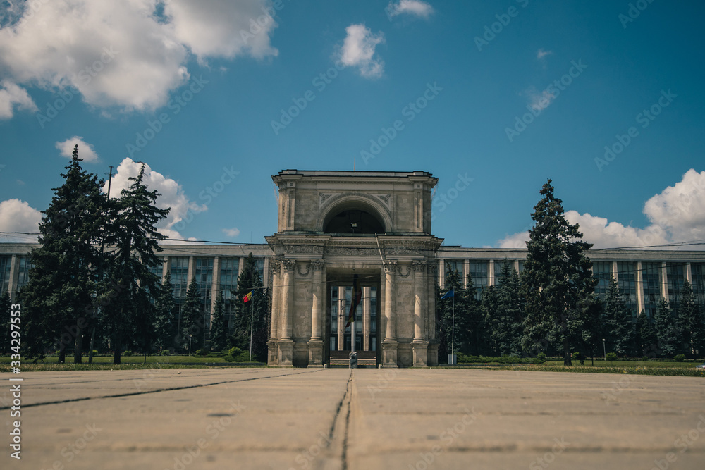Obraz premium The Triumphal Arch in front of the Government building in Chisinau, Moldova on a warm summer day. Frog view photo
