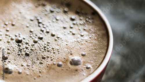 cup of coffee with bubbles on the surface fragment blurred background