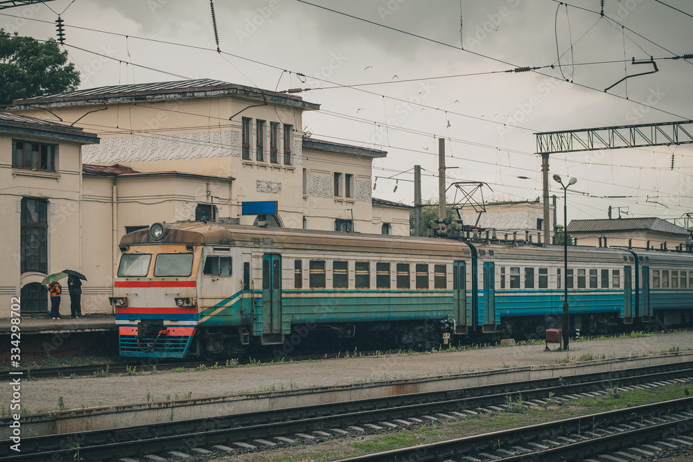 Ukrainian passenger train on the station of Zhmerynka during a small rain shower. Train waiting at the platform. Zhmerynka is an important rail junction in Ukraine Ukrainian passenger train on the station of Zhmerynka during a small rain shower. Train waiting at the platform. Zhmerynka is an important rail junction in Ukraine