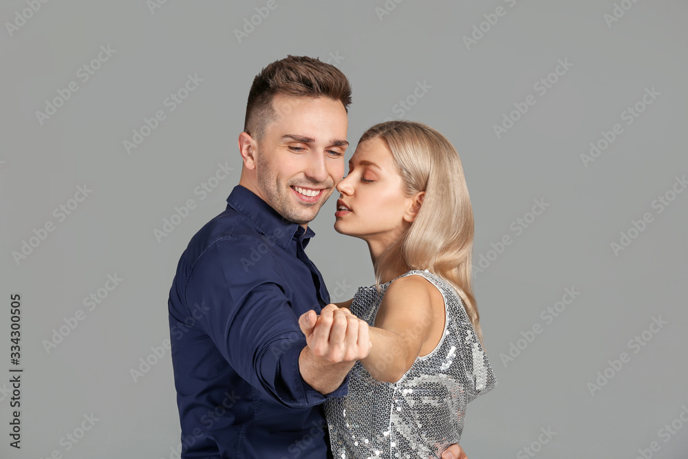 Happy dancing young couple on grey background Happy dancing young couple on grey background